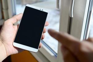 A man is holding a smartphone with an empty black screen in his hand. Copy space for text photo