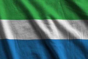 Sierra Leone flag with big folds waving close up under the studio light indoors. The official symbols and colors in banner photo