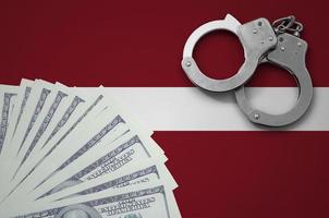 Latvia flag with handcuffs and a bundle of dollars. The concept of illegal banking operations in US currency photo
