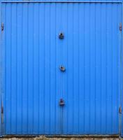Texture of a metal blue wall with a gate closed for three locks photo