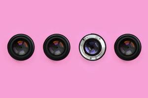 A few camera lenses with a closed aperture lie on texture background of fashion pastel pink color paper in minimal concept. Abstract trendy pattern photo