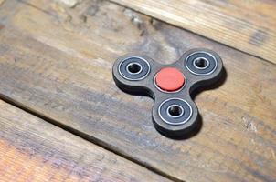 A rare handmade wooden fidget spinner lies on a brown wooden background surface. Trendy stress relieving toy photo