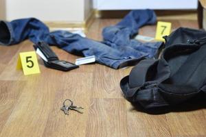 Crime scene investigation - numbering of evidences after the murder in the apartment. Keys, wallet and clothes with evidence markers photo