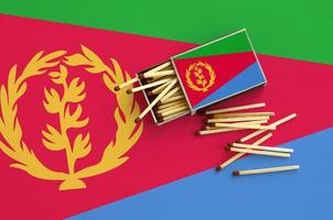 Eritrea flag is shown on an open matchbox, from which several matches fall and lies on a large flag photo