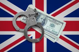 Great britain flag with handcuffs and a bundle of dollars. Currency corruption in the country. Financial crimes photo