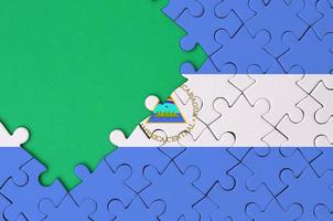 Nicaragua flag is depicted on a completed jigsaw puzzle with free green copy space on the left side photo