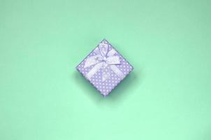 Small lilac gift box lie on texture background of fashion pastel green color paper photo