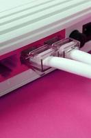 The Internet cable plugs are connected to the Internet router, which lies on a bright pink background. Items required for Internet photo
