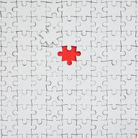 The texture of a white jigsaw puzzle in an assembled state with one missing element forming a red space photo