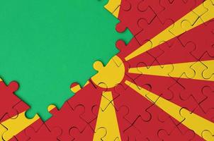 Macedonia flag is depicted on a completed jigsaw puzzle with free green copy space on the left side photo