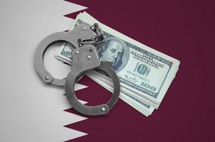 Qatar flag with handcuffs and a bundle of dollars. Currency corruption in the country. Financial crimes photo