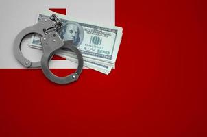 Tonga flag with handcuffs and a bundle of dollars. The concept of breaking the law and thieves crimes photo