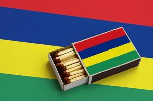 Mauritius flag is shown in an open matchbox, which is filled with matches and lies on a large flag photo