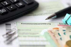 German income tax return form with pen and european euro money bills lies on accountant table close up. Taxpayers in Germany using euro currency to pay taxes photo