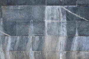 The texture of a wall of large granite tiles that are covered with white streaks when exposed to dampness photo