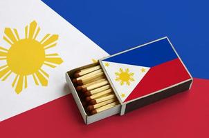 Philippines flag is shown in an open matchbox, which is filled with matches and lies on a large flag photo