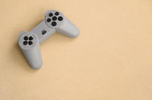 Playing games concept. Single pad joystick lies on the blanket of furry orange fleece fabric. Controller for video games on a background texture of light orange soft plush fleece material photo