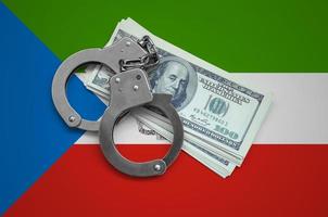 Equatorial Guinea flag with handcuffs and a bundle of dollars. Currency corruption in the country. Financial crimes photo