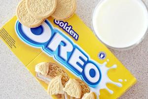 TERNOPIL, UKRAINE - MAY 28, 2022 Oreo golden crispy cookies with glass of milk on white background. The brand Oreo is owned by company Mondelez international photo