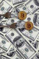 Bitcoin getting New Hard Fork Change, Physical Golden Crytocurrency Coin under the fork on the dollars background. Blockchain Transaction System Crisis Concept photo