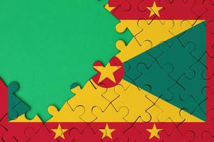 Grenada flag is depicted on a completed jigsaw puzzle with free green copy space on the left side photo