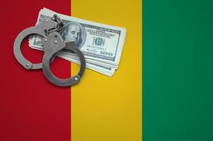 Guinea flag with handcuffs and a bundle of dollars. The concept of breaking the law and thieves crimes photo