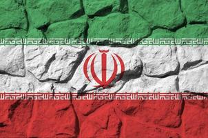 Iran flag depicted in paint colors on old stone wall closeup. Textured banner on rock wall background photo