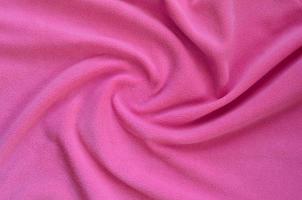 The blanket of furry pink fleece fabric. A background of light pink soft plush fleece material with a lot of relief folds photo