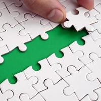 The human hand paves the way to the surface of the jigsaw puzzle, forming a green space. The concept of overcoming the difficulties on the way to success photo