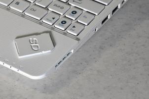 A compact SD memory card lies on a white netbook. The digital information storage device is ready for use. Concept of modern technologies photo