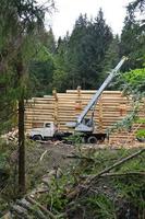 The process of building a wooden house from wooden beams of cylindrical shape. Crane in working condition. photo