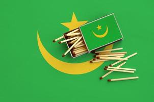 Mauritania flag is shown on an open matchbox, from which several matches fall and lies on a large flag photo
