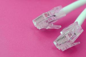 cable blanco con conector rj45 sobre un fondo rosa brillante. enchufes de red ethernet foto