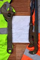 Adjustable wrenches and paper lies of an orange and green signal worker shirts photo
