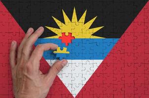 Antigua and Barbuda flag is depicted on a puzzle, which the man's hand completes to fold photo