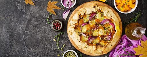 Galette pie with pumpkin and mozzarella cheese on dark background. Thanksgiving day food. Banner. Top view. photo