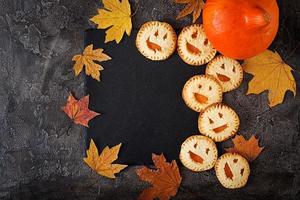 Homemade  cookies in the form as Halloween  jack-o-lantern pumpkins  on the dark table. Top view. photo