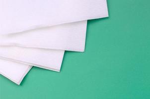 Several white paper napkins lie on a plastic green background photo