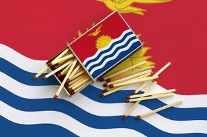 Kiribati flag is shown on an open matchbox, from which several matches fall and lies on a large flag photo