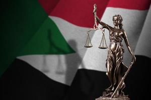 Sudan flag with statue of lady justice and judicial scales in dark room. Concept of judgement and punishment photo