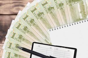 1 Chinese yuan bills fan and notepad with contact book and black pen. Concept of financial planning and business strategy photo