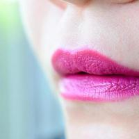 Close up shot of woman lips with glossy fuchsia lipstick photo