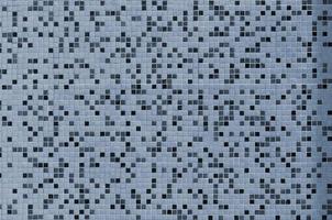 The texture of the wall, decorated with a mosaic of various small square tiles. Abstract pattern of ceramic tiles on the wall photo