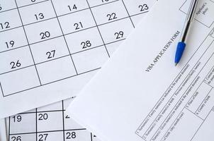 formulario típico de solicitud de visa y bolígrafo azul en la página del calendario de papel foto