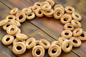 A lot of fresh yellow bagels lie on the surface of the old dark wood. A popular kind of flour products. One of the traditional Russian treats for tea photo