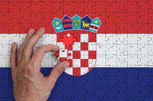 Croatia flag is depicted on a puzzle, which the man's hand completes to fold photo