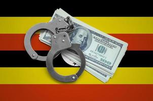 Uganda flag with handcuffs and a bundle of dollars. Currency corruption in the country. Financial crimes photo