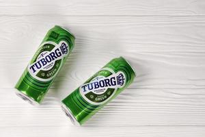 KHARKOV, UKRAINE - DECEMBER 8, 2020 Aluminium cans of green Tuborg beer on wooden background. Tuborg is Danish brewing company founded in 1873 photo