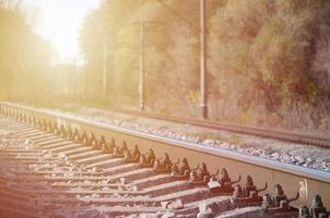 Autumn industrial landscape. Railway receding into the distance among green and yellow autumn trees photo