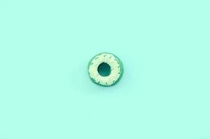 Single small plastic donut lies on a pastel colorful background. Flat lay minimal composition. Top view photo